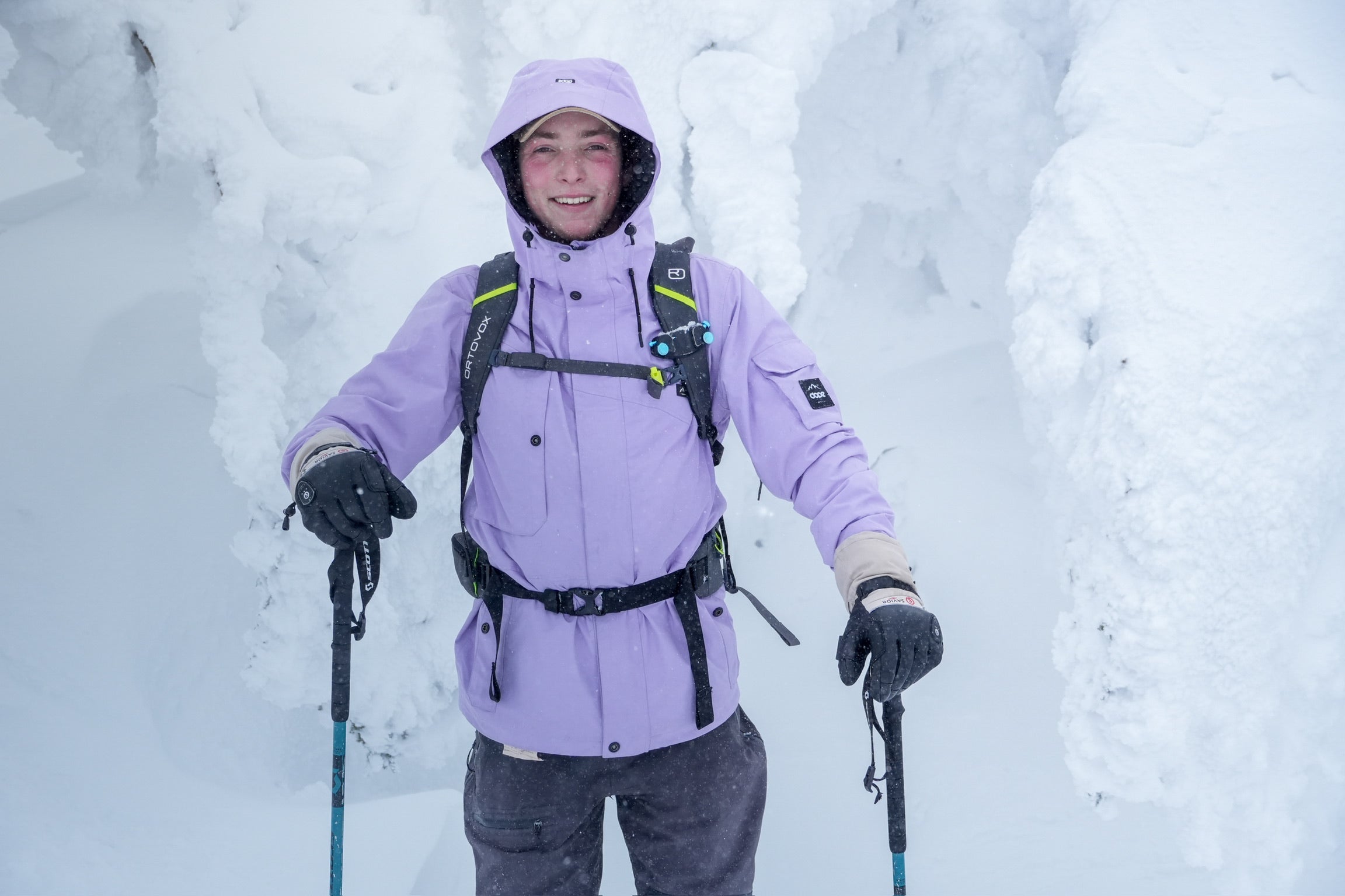 Hiker in deep winter snow wearing insulated gloves and cold-weather gear, holding trekking poles during a snowy mountain trek.