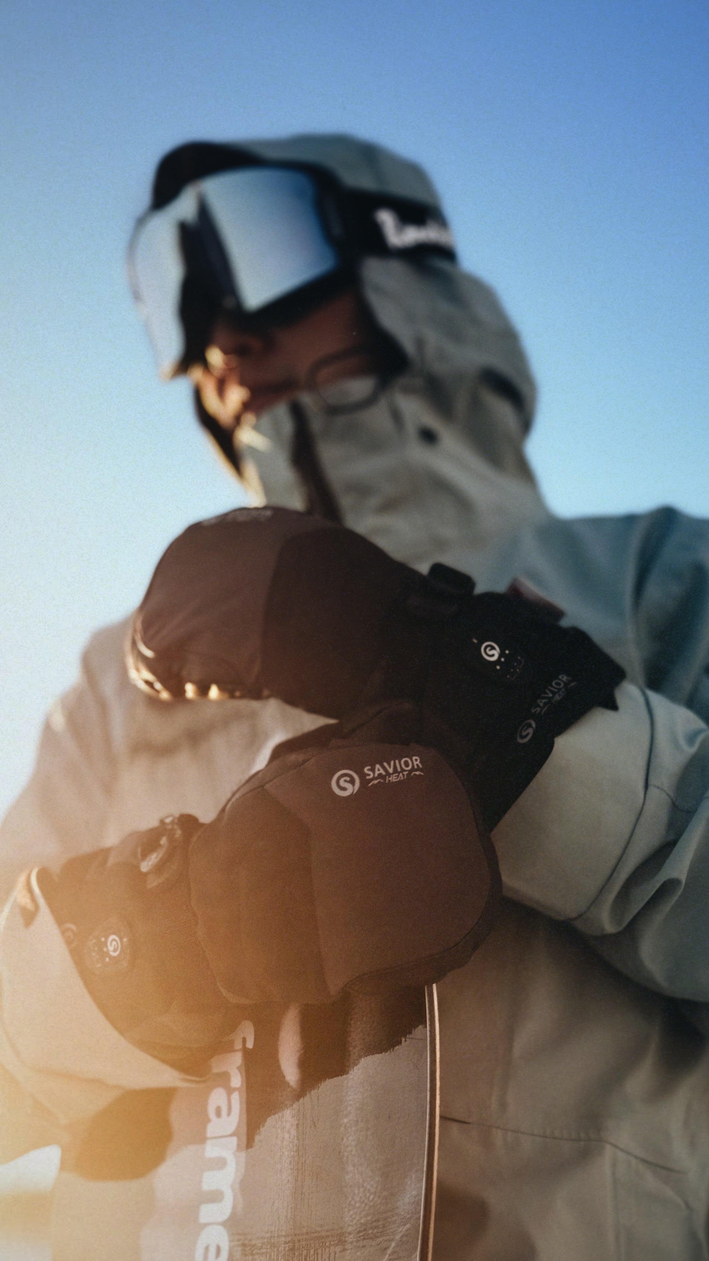 Skier wearing battery heated gloves while adjusting gear in cold sunrise, showcasing winter warmth and outdoor performance.