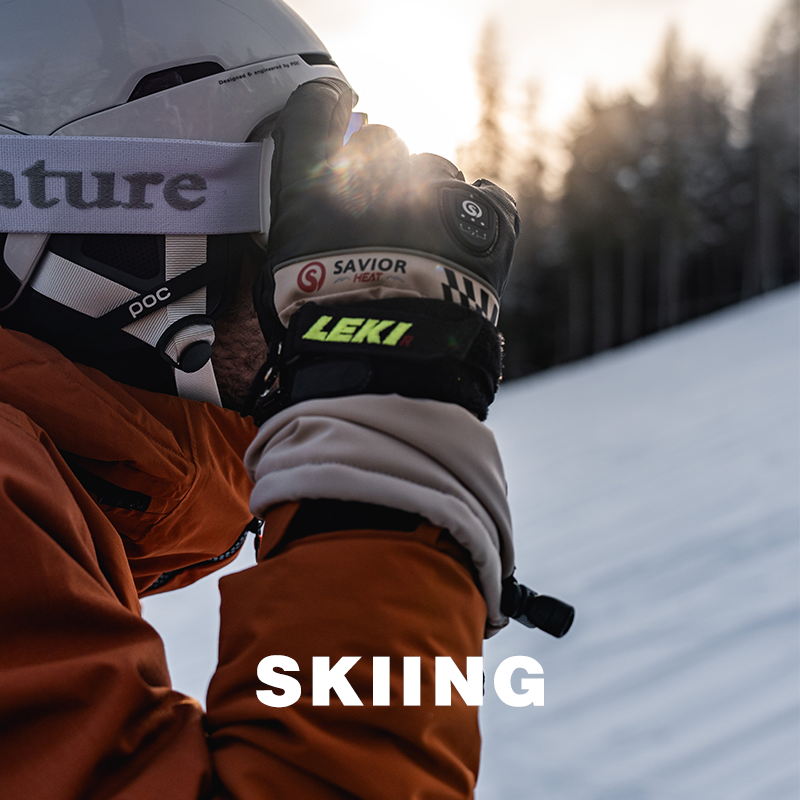 A skier wearing SAVIOR HEAT heated gloves, preparing to ski in cold mountain conditions.
