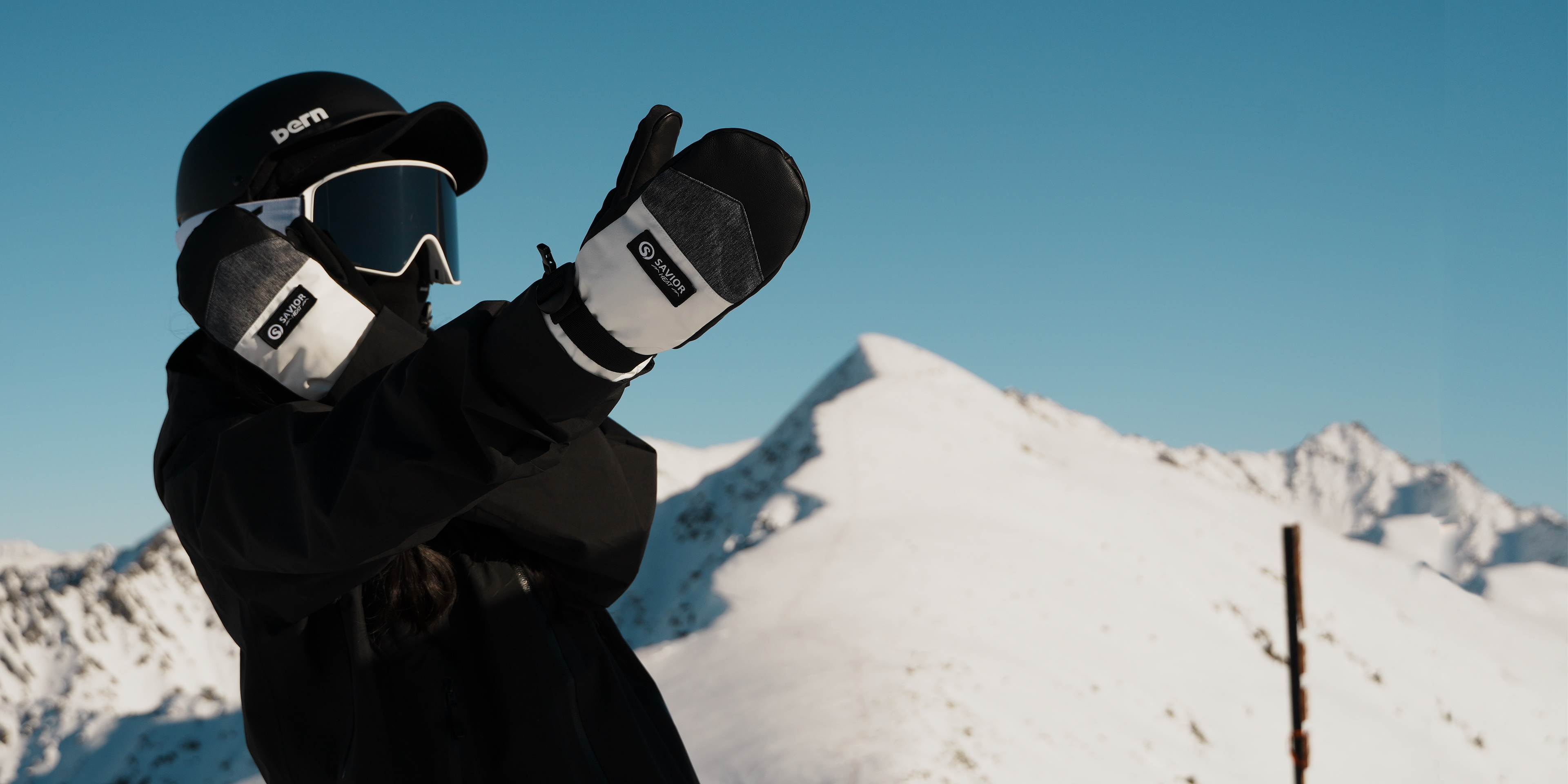 Skier wearing SAVIOR HEAT heated mittens on a snowy mountain.
