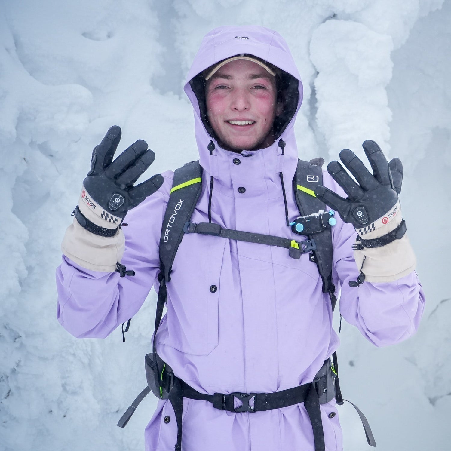 Smiling skier in snowy terrain wearing insulated winter gloves, lifting hands to show warmth and protection in extreme cold conditions.