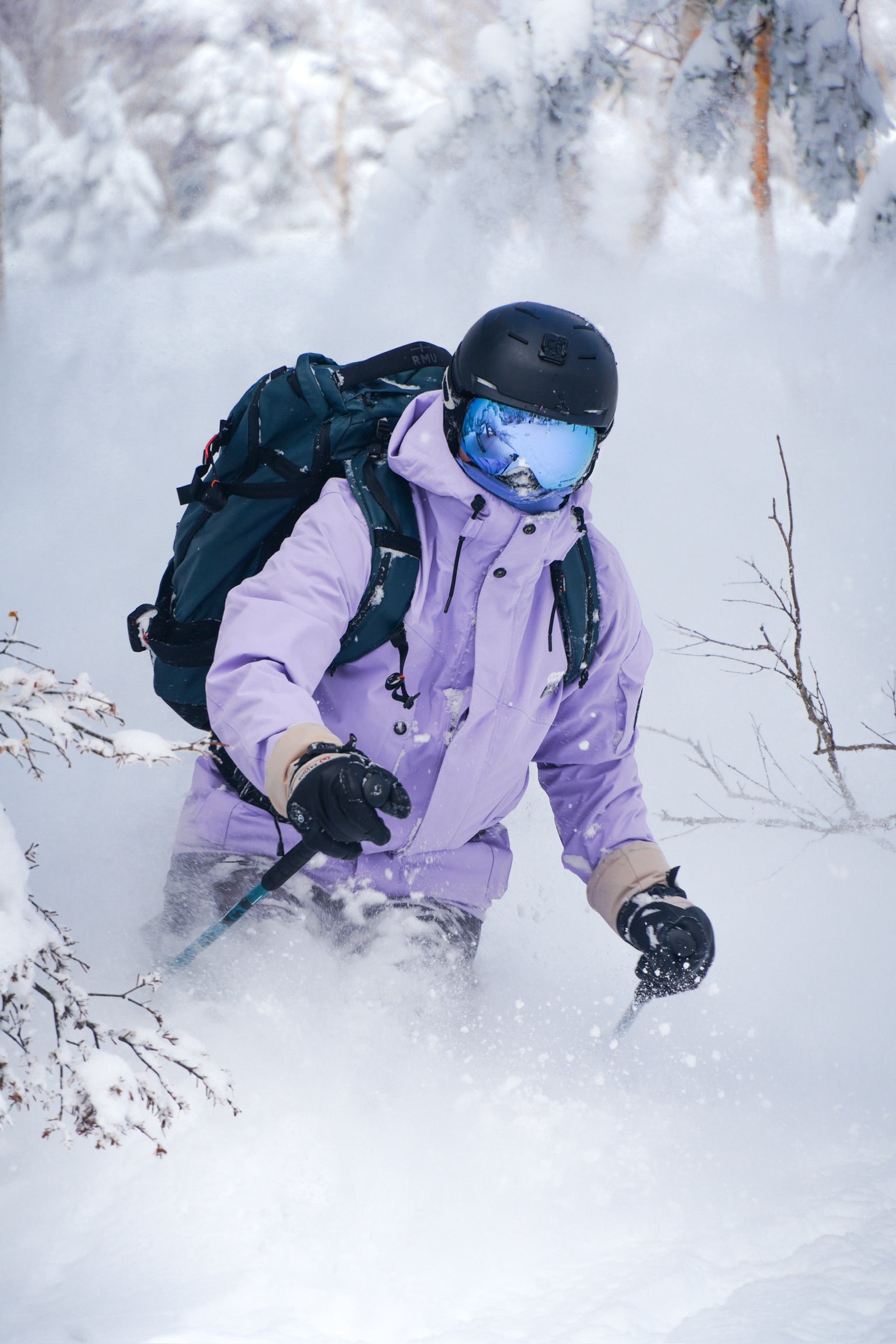 Snow skier in deep powder wearing insulated gloves, helmet, and backpack, moving through cold winter terrain during a backcountry run.