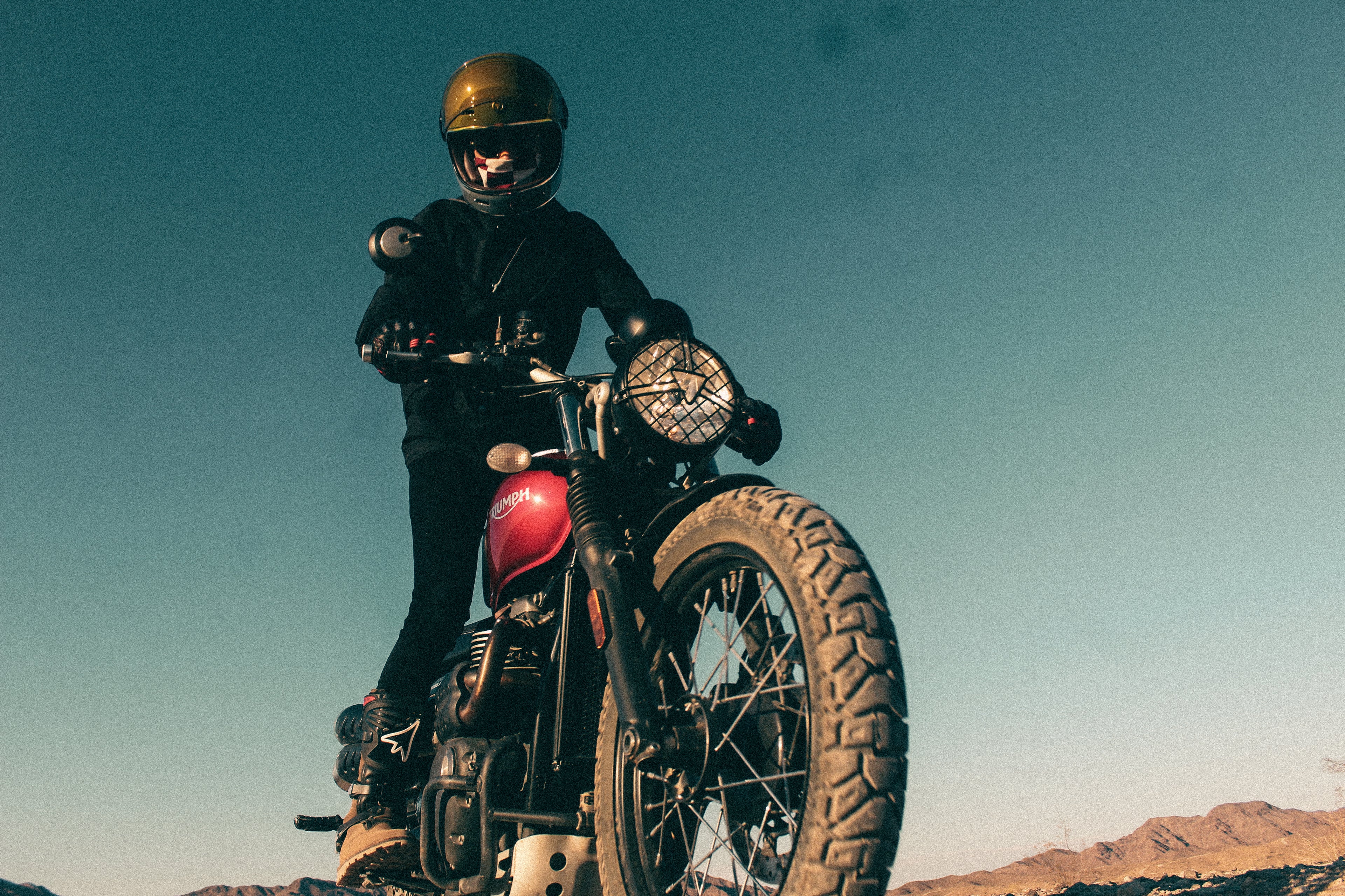 Motorcyclist riding a classic bike on an open road under a clear sky