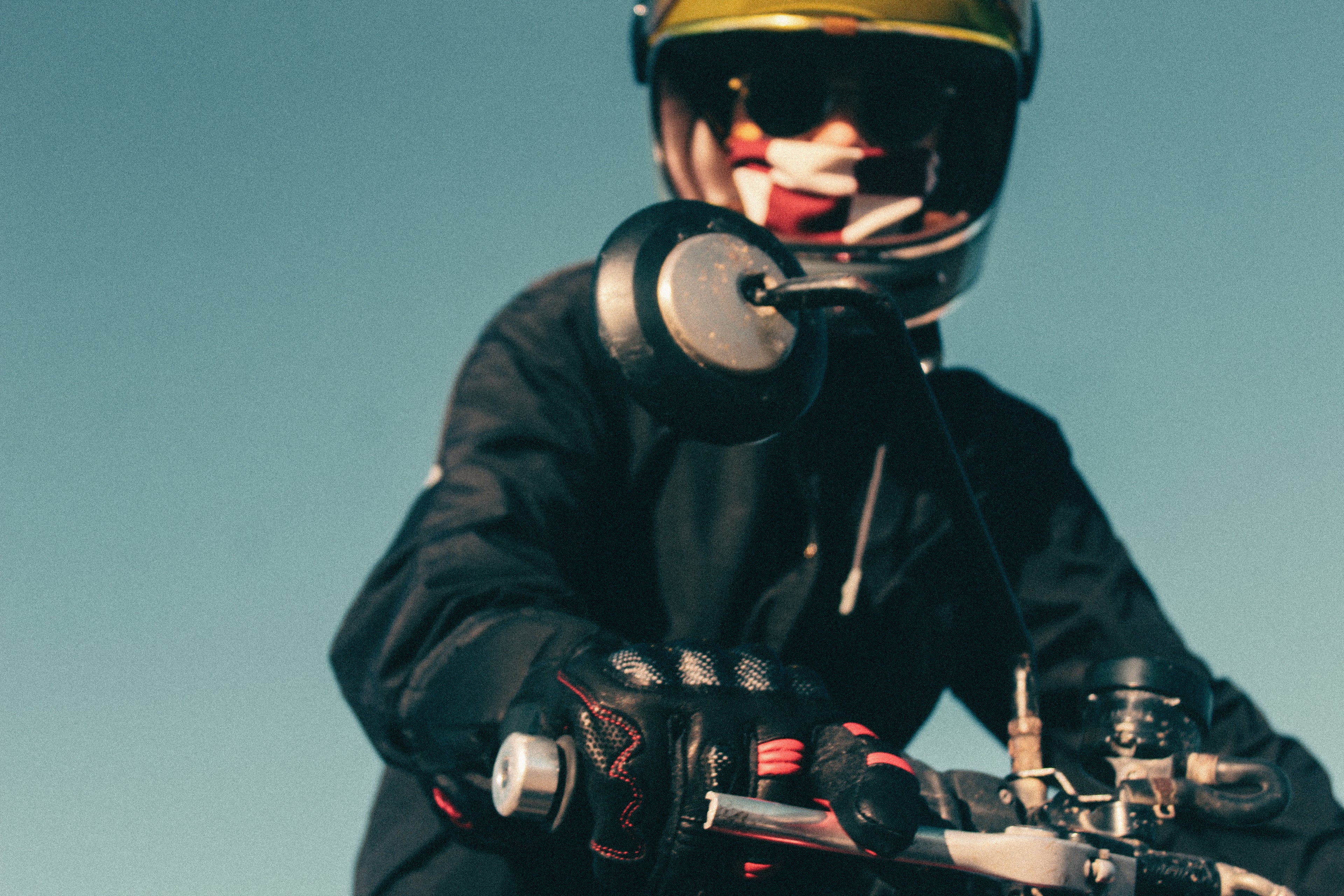Motorcyclist wearing heated riding gloves while gripping a motorcycle throttle outdoors.