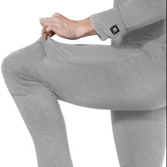 Person wearing gray heated underwear, stretching the elastic fabric at the knee with a visible power button on the cuff.