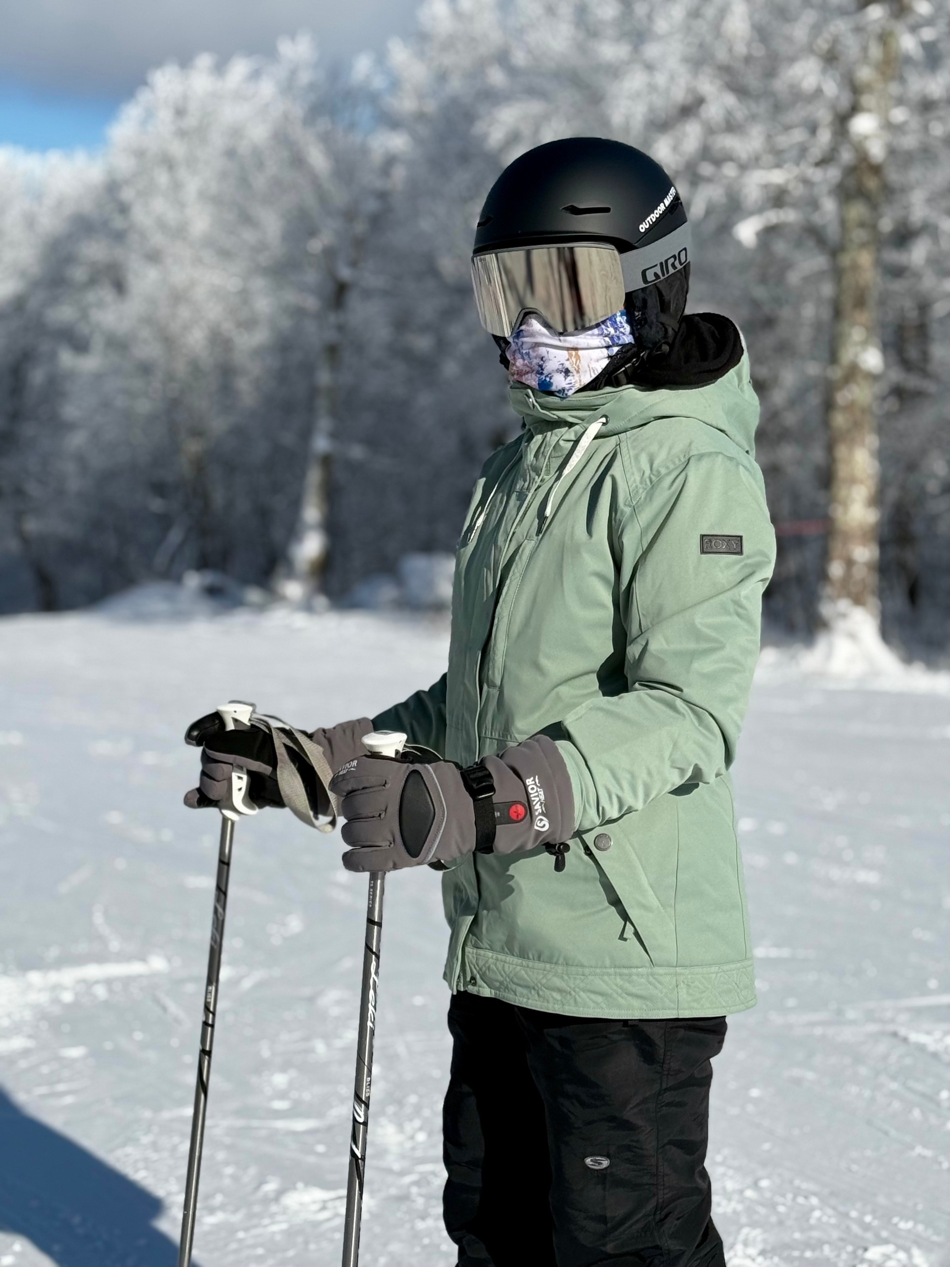 Skier standing on a snowy slope wearing winter heated gloves, showing reliable warmth and grip for cold-weather skiing and outdoor adventures.