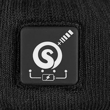 Power button with battery indicator on black heated socks, showing control icon stitched into knit fabric.