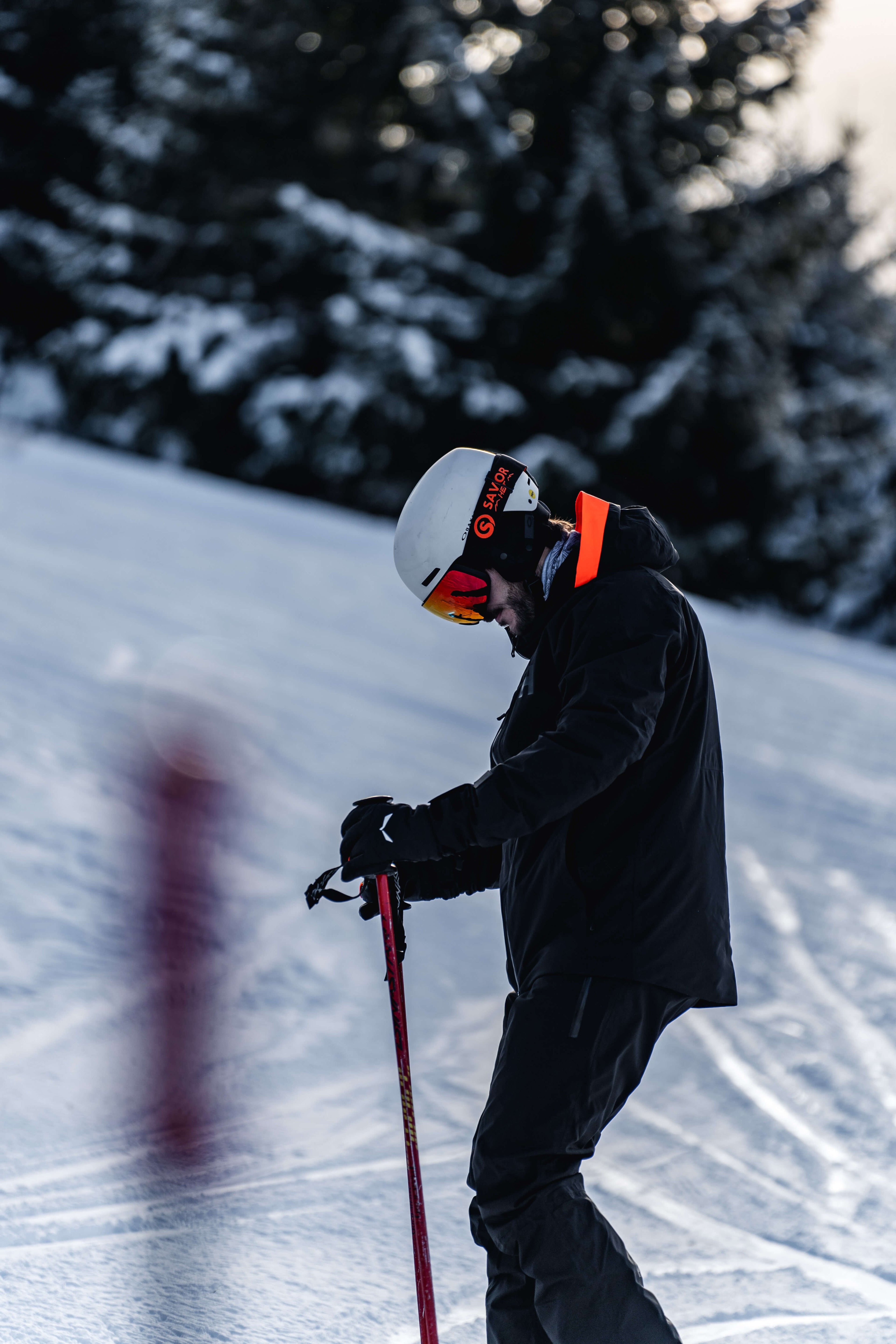 Skier wearing best heated ski gloves on mountain slope with snow-covered pine trees